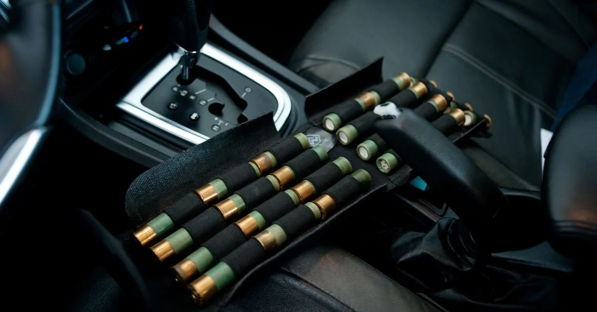Cartouches de fusil de chasse rangées dans l'habitacle d'une voiture, près du levier de vitesse. Gros plan détaillé du véhicule.