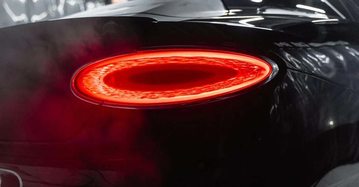 Vue rapprochée mettant en valeur le design élégant du feu arrière éclairé d'une voiture de luxe noire.